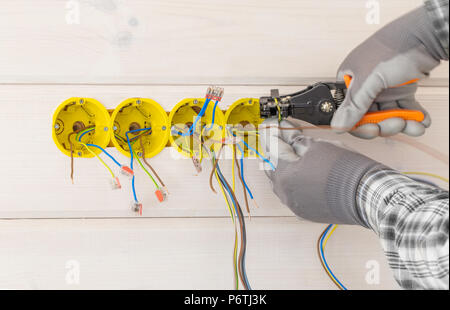 hands of electrician installing electrical socket with screwdriver in the wall Stock Photo