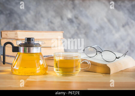 A cup of tea and tea pot with books on table in reading time Stock Photo