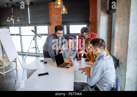 Diverse young people in casual cloth, working together on making marketing research. University students share opinions during break sitting in cowork Stock Photo