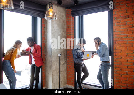 Three multiethnic male business partners and his financial consultant female brainstorming and working out development strategy for next year Stock Photo
