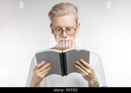 Handsome blond srudent man in spectacles reading grey book, preparing to exams in colledge, isolated over white background with copy space Stock Photo