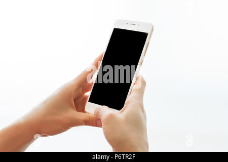 Female hands holding smartphone with black screen isolated on white background. Mobile device close up. Mock up concept Stock Photo