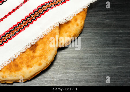 Two fresh pita bread under multicolor napkin. Wooden texture. Rustic food background. Top view. Copy space Stock Photo
