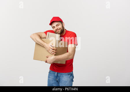 Delivery young man in red uniform huging empty cardboard boxes isolated on white background. Copy space for advertisement Stock Photo