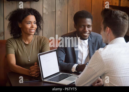 Caucasian realtor consulting black customers at cafe meeting Stock Photo