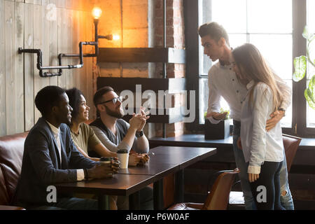 Caucasian man introducing girlfriend to friends at cafe Stock Photo