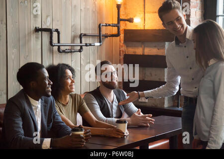 Smiling worker introducing new employee to colleagues during caf Stock Photo