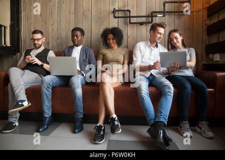 Multiracial people addicted to gadgets not talking to each other Stock Photo