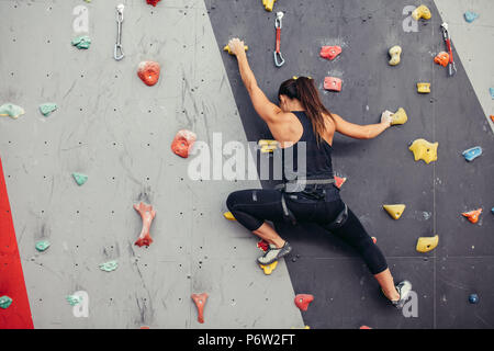 Female fitness professional climber training at bouldering gym. Muscular  woman with athletic body dressed in black, climbing on artificial colourful  r Stock Photo - Alamy