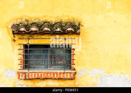 Barred & shuttered window in yellow wall, Central America Stock Photo