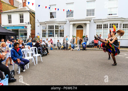 Two can-can girls dancing and kicking their legs up on a street in front of audience sitting watching during Le Weekend, French event at Sandwich town Stock Photo