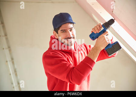 Portrait of young repairman using hammer drill driver at the construction site. Stock Photo