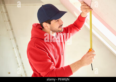 Portrait of young man using measuring tape while working on construction site. Stock Photo