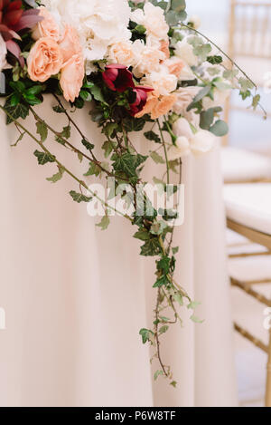 Decoration of a wedding table of newlyweds greens and in flowers. Long, hanging on a table, composition from are fresh flowers Stock Photo