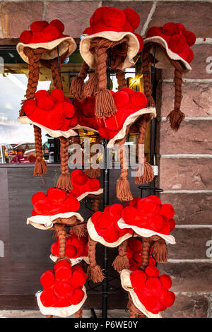 Colorful red traditional woollen bollenhut, part of the regional folk costume, hanging on a stand outside a shop in the Black Forest region of Germany Stock Photo
