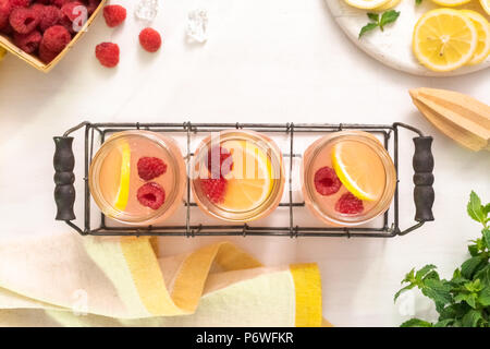 Raspberry lemonade in drinking mason jars on a white table. Stock Photo