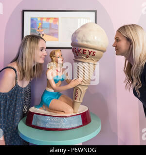 London, UK.  3 July 2018. Staff members pose with 20th century ice cream advertising at a preview of 'SCOOP: A Wonderful Ice Cream World', the first official exhibition of the British Museum of Food.  The exhibition presents items from the Robin and Caroline Weir Collection and explores the science and appeal of ice cream going back 400 years.  The exhibition takes place at the Gasholders near Granary Square in Kings Cross and runs 3 July to 30 September 2018. Credit: Stephen Chung / Alamy Live News Stock Photo