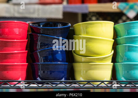 Brightly colored ceramic bowls are stacked on a shelf for sale at an antique festival. Stock Photo
