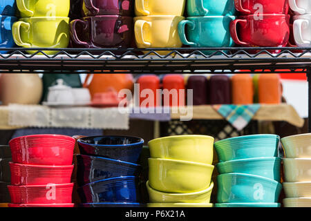 Colorful coffee mugs and bowls sit on shelf for sale at antique festival. Stock Photo
