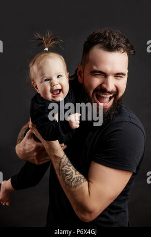 Family values concept. Studio portrait of adorable innocent funny one year old baby girl smiling with his happy joyful father. Stock Photo