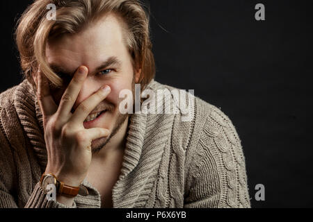 close up portrait of brutal man laughing and closing his face with hand Stock Photo