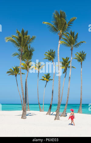 Juanillo Beach (playa Juanillo), Punta Cana, Dominican Republic. Woman walking on a palm-fringed beach (MR). Stock Photo