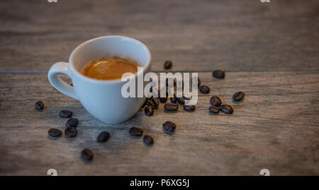 Espresso with crema in a white cup with coffee beans on a light wood background. Stock Photo