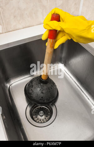 hand using a plunger to cleaning a clogged sink Stock Photo