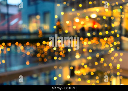 Christmas illumination in a shopping center with a background of glowing lights. Blurry Stock Photo