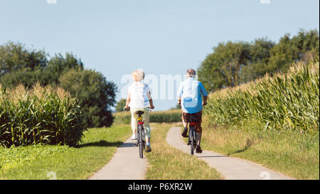 Senior couple looking forward with confidence while riding bicycles Stock Photo