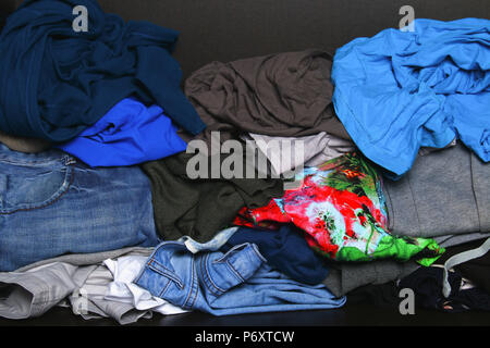 A pile of different clothes is lying on the shelf in the closet Stock Photo