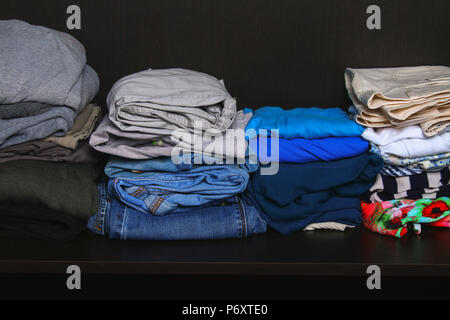 Neat stacks of different clothes lie on a shelf in the closet Stock Photo