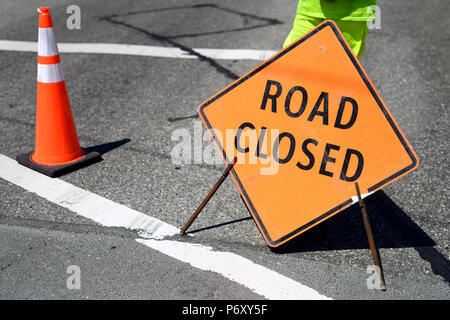 Road closed ahead traffic sign on the road with a body part of construction flagger Stock Photo