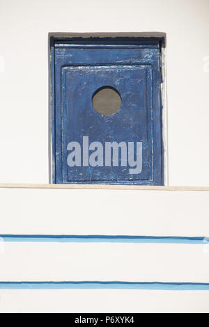 Old, blue wooden storage space ? set into wall with a small opening, in Mirties, Kalymnos, Greece Stock Photo