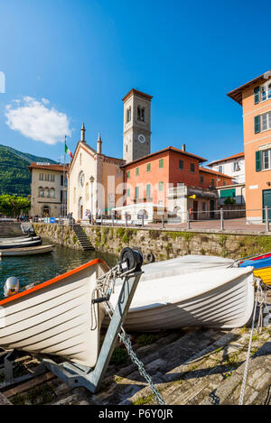 Torno, lake Como, Como province, Lombardy, Italy. Morred boats and the town's church at the jetty, Stock Photo