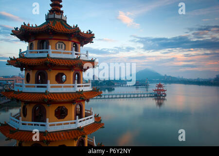 Taiwan, Kaohsiung, Lotus pond, Dragon and Tiger Tower Temple with view of bridge leading to Spring and Autumn pagodas and statue of Syuan Tian Emperor in background Stock Photo