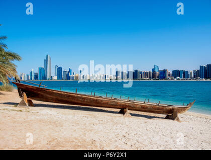 Traditional boat in the Heritage Village with city skyline in the background, Abu Dhabi, United Arab Emirates Stock Photo