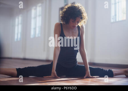 Strong young female dancer stretching, doing the splits in dance studio Stock Photo