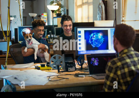 Creative business people with dog in open plan office Stock Photo