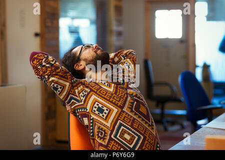 Creative businessman stretching at desk in office Stock Photo