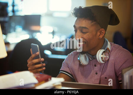 Smiling creative businessman texting with smart phone in office Stock Photo