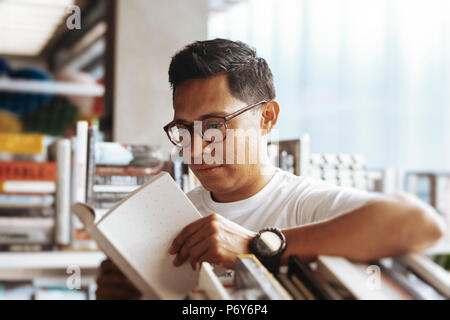 Young man reading book in a book store. Stock Photo