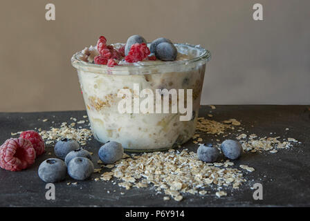 Jar of overnight oats with fruit and oatmeal on black slate Stock Photo