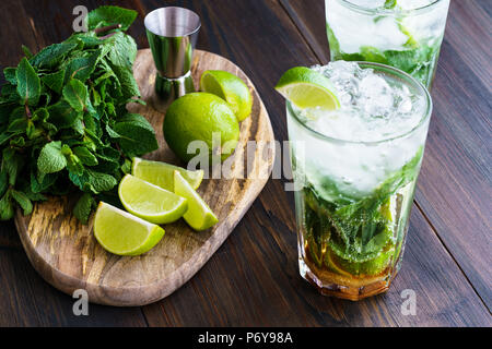 Dirty mojito and ingredients (fresh mint, sliced lime) served on a dark wooden board. High resolution. Stock Photo