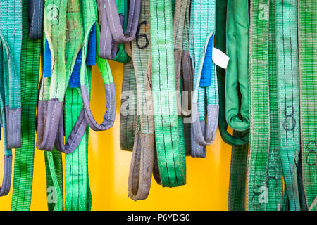 Worn numbered green ropes hanging in different lenghts on yellow background Stock Photo