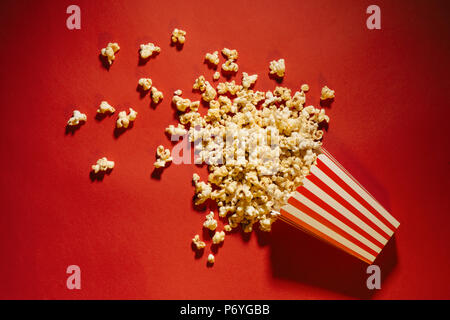 Spilled popcorn on a red background, cinema, movies and entertainment concept Stock Photo