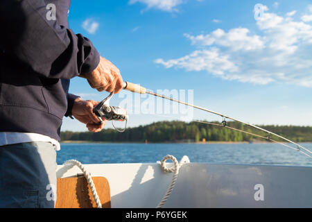 The hands of an adult man holding a sport fishing rod with reel