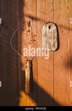 Old handmade fishing tools hanging on orange wood wall on sunlight Stock Photo