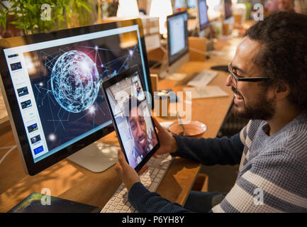 Graphic designer video chatting with colleague on digital tablet in office Stock Photo