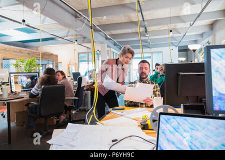 Creative business people discussing paperwork in open plan office Stock Photo